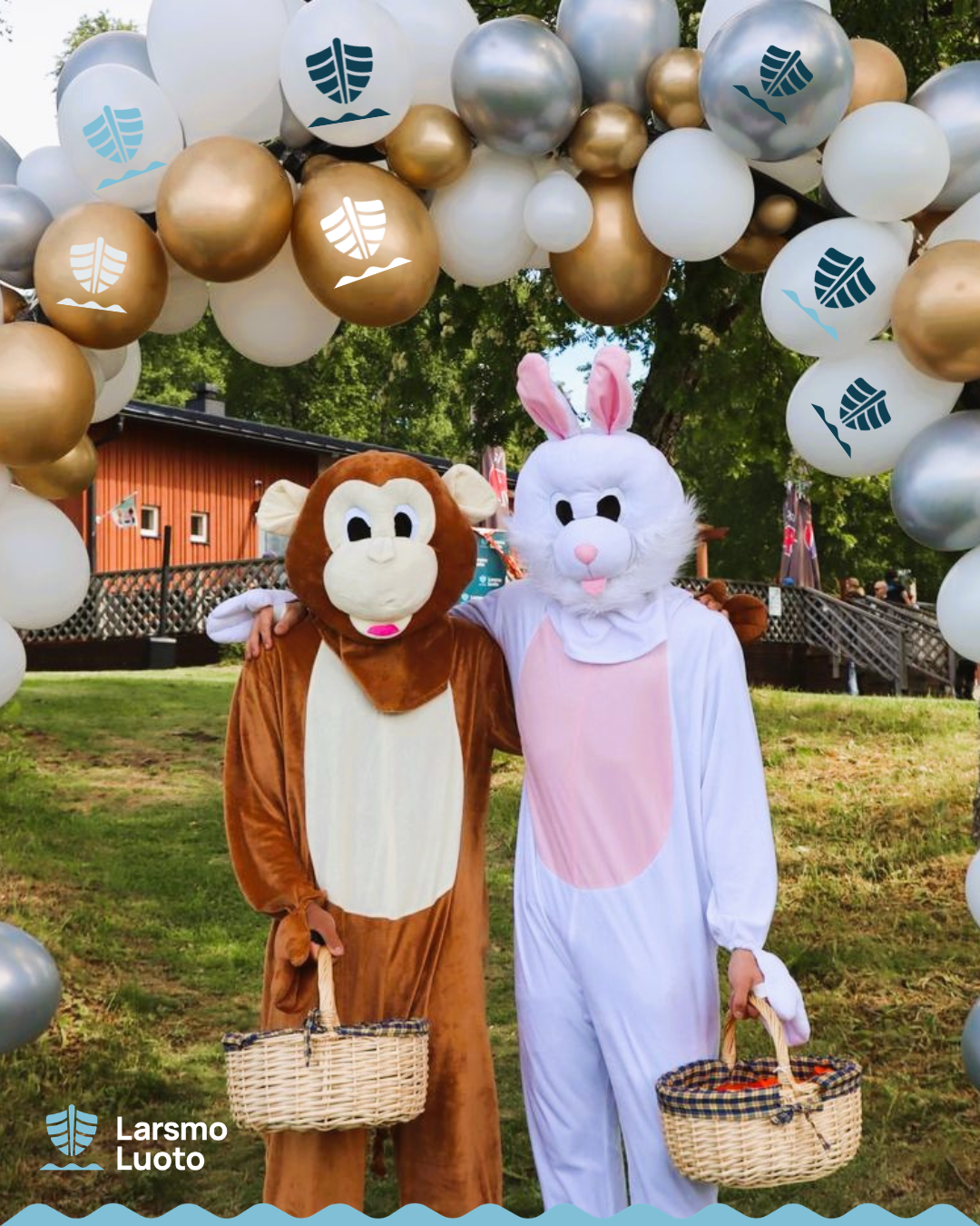 Två maskotar utklädda till apa och kanin poserar under en båge av ballonger med Larsmo kommuns logo